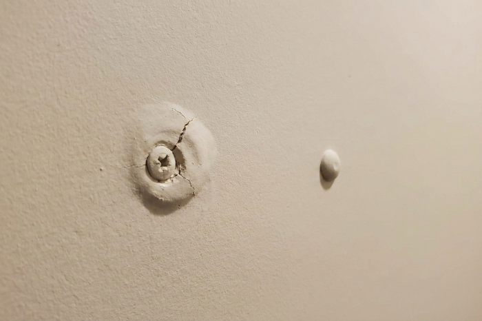 Drywall nail pop caused by home settling and loose fasteners