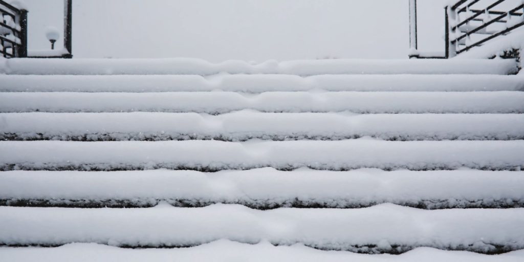 Snow-covered front steps and railing at a Pittsburgh home after a winter storm