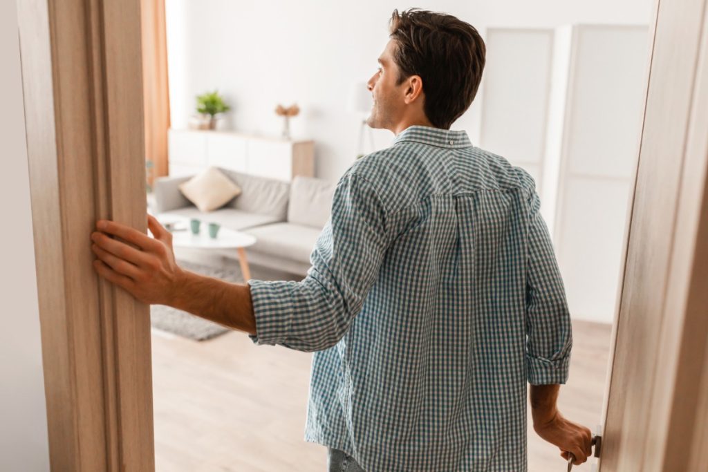 New homeowner walking through a living room while checking items on a monthly home maintenance checklist