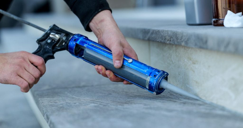 caulk gun being use on exterior steps in summer