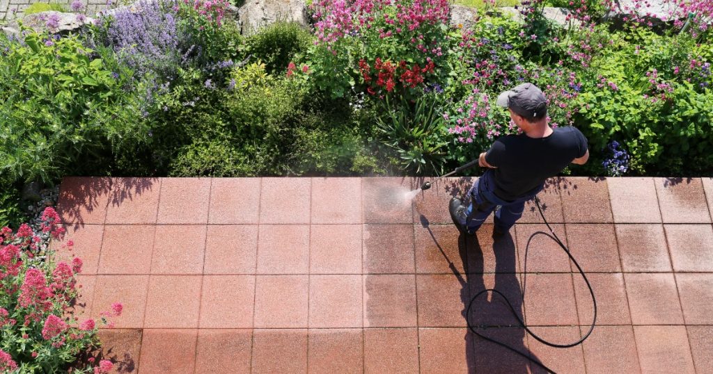 pressure washing a dirty patio to prepare exterior spaces for summer