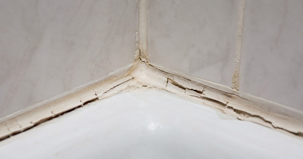 Close-up of dried, cracked caulk seam in a shower corner