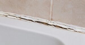 Cracked and peeling caulk along the edge of a bathroom bathtub