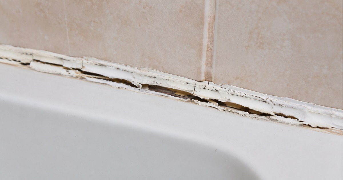 Cracked and peeling caulk along the edge of a bathroom bathtub
