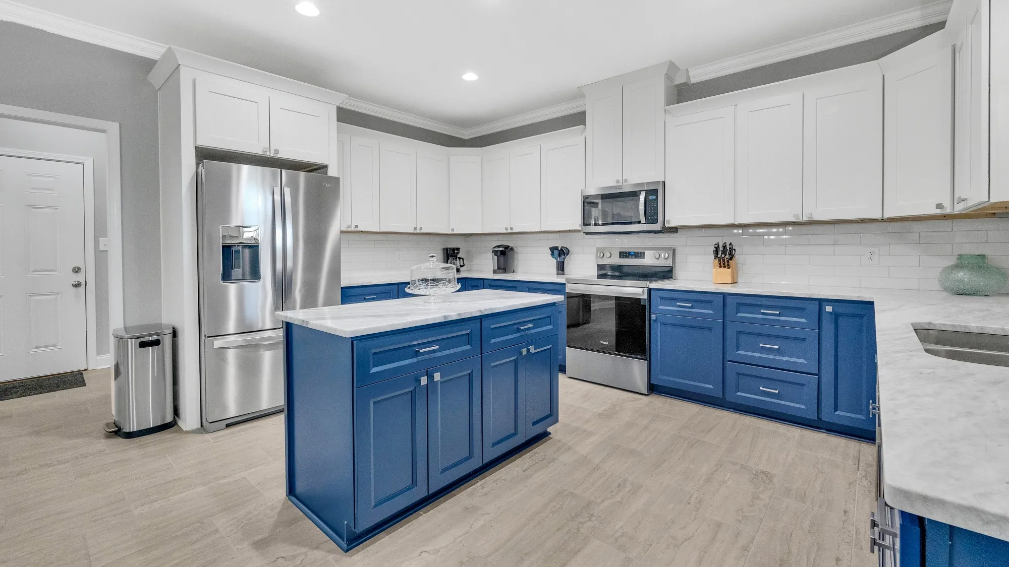 Renovated kitchen with white cabinets and a blue island