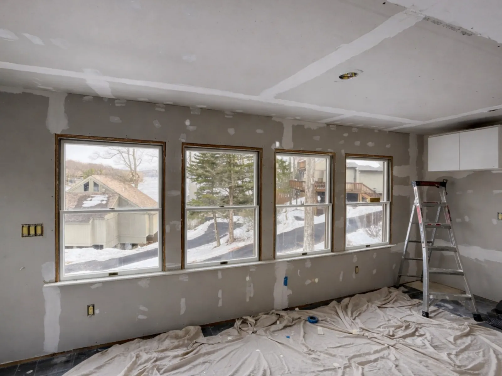 Gutted kitchen with exposed subfloor and large windows