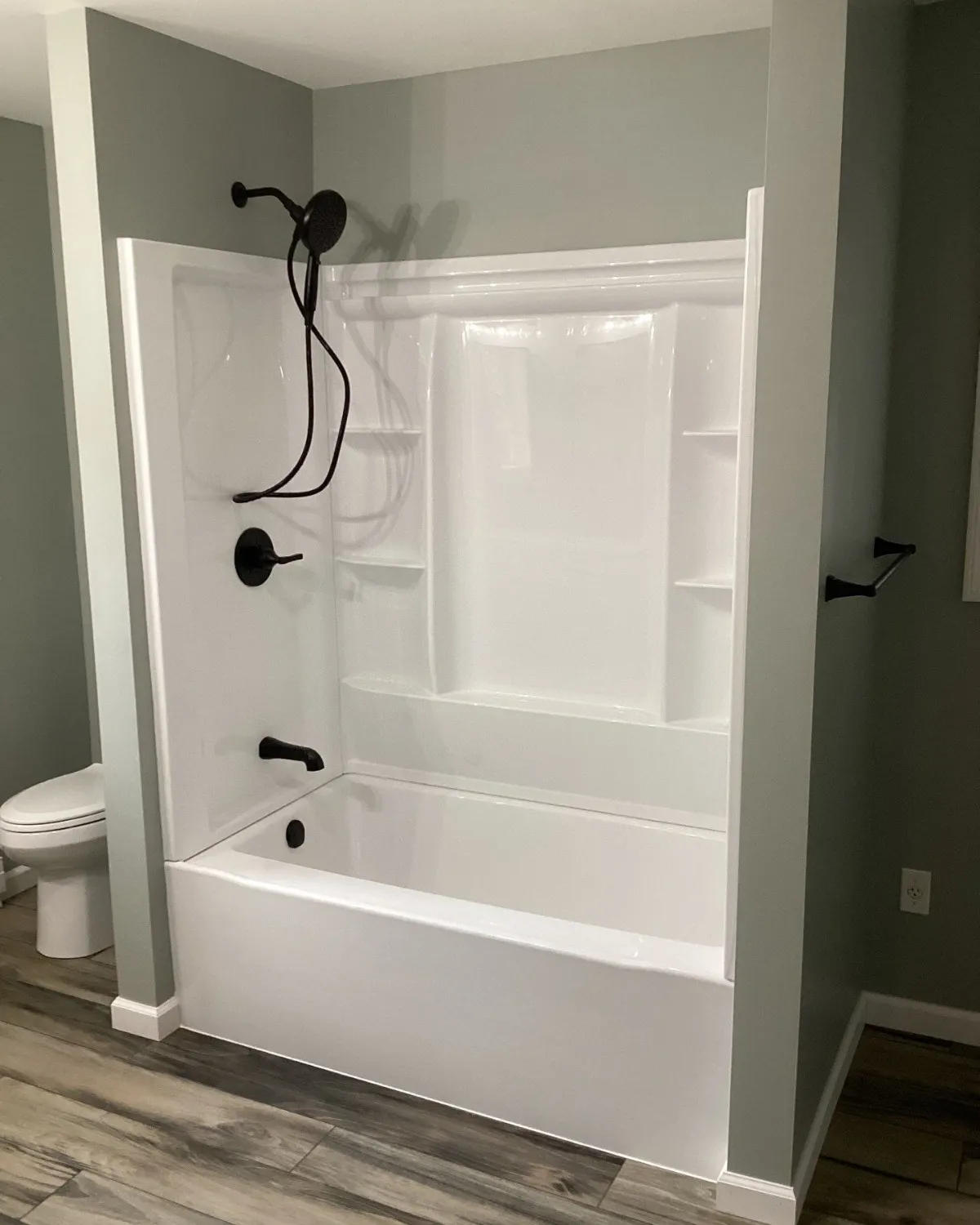 Completed white tub and shower surround with black fixtures