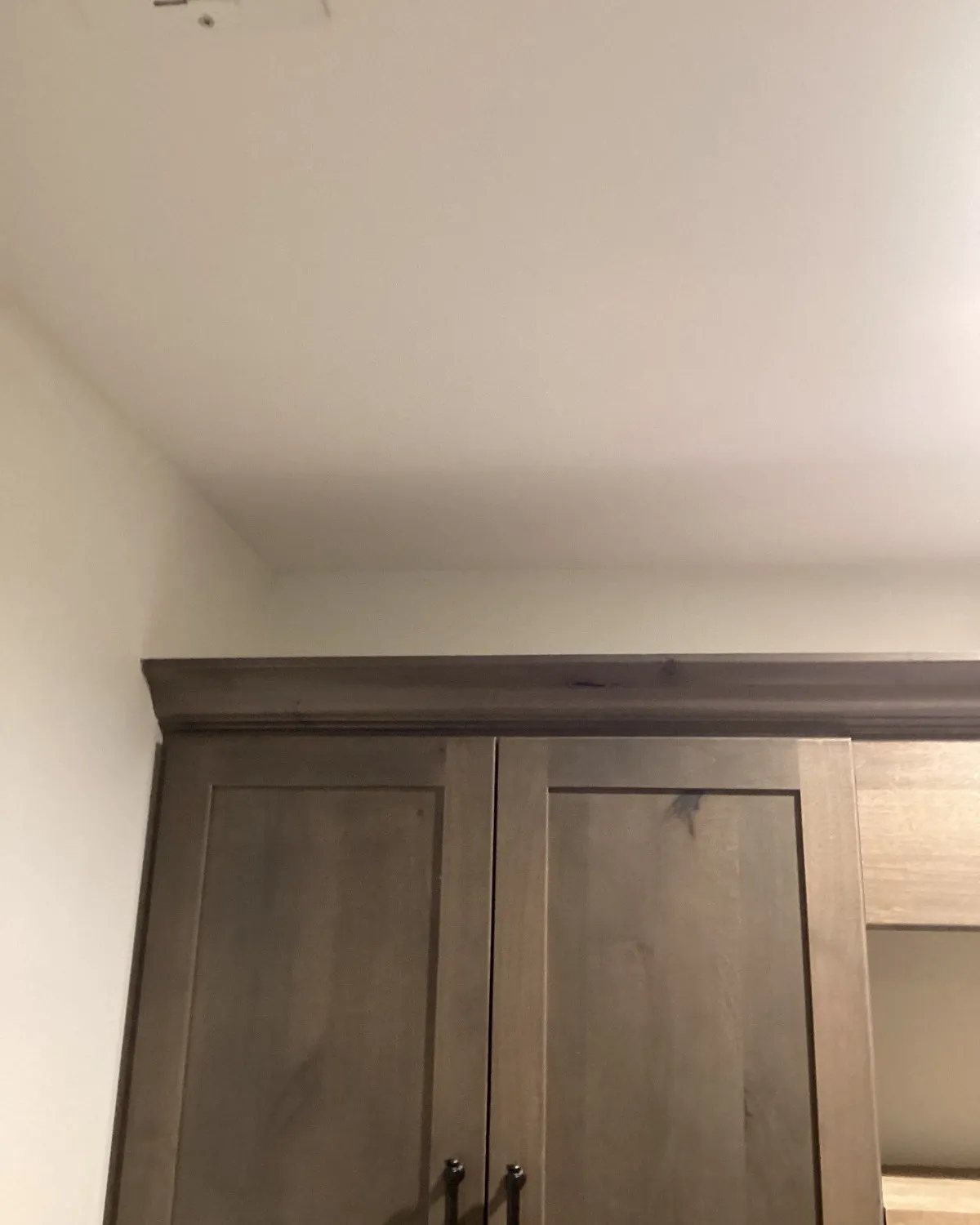 Finished wall and ceiling above a gray cabinet after water damage