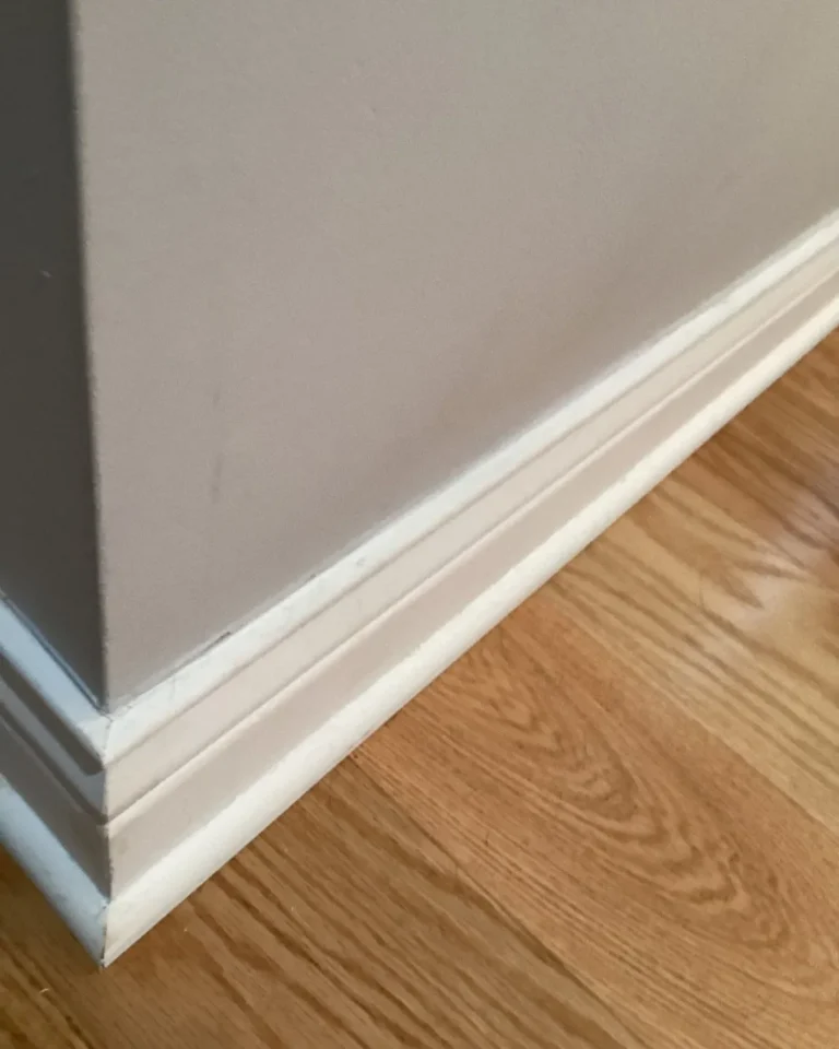 White baseboard installed above a hardwood floor