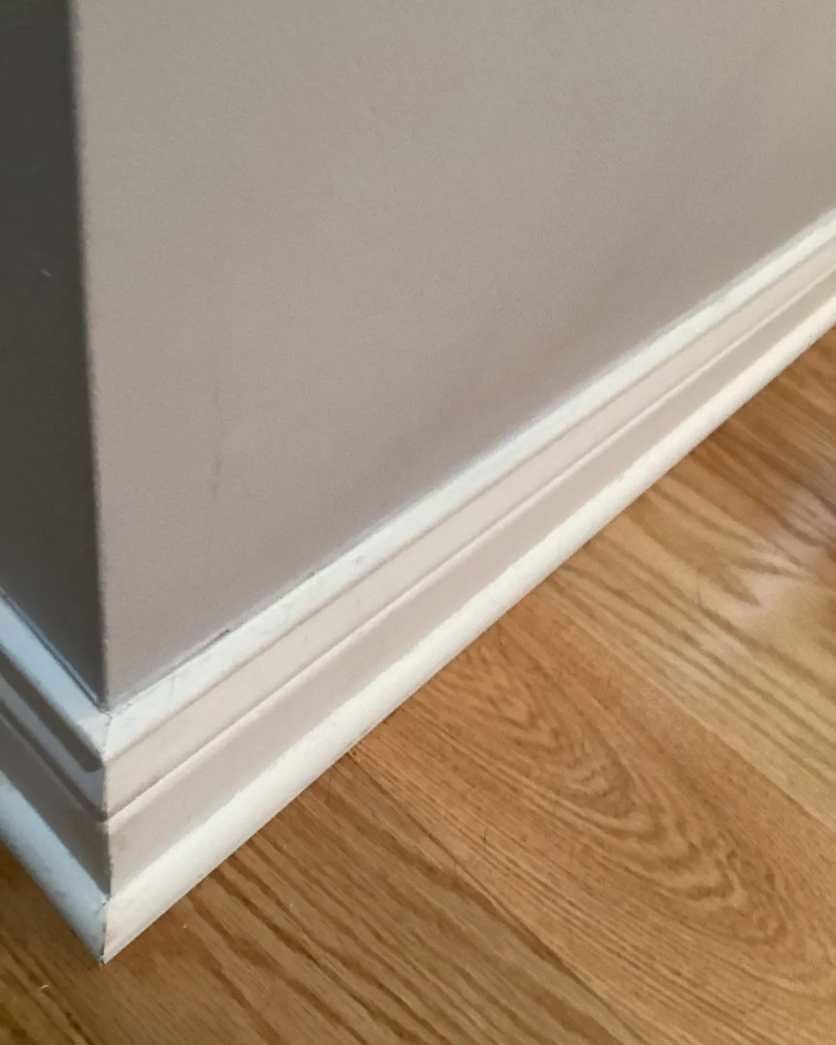 White baseboard installed above a hardwood floor