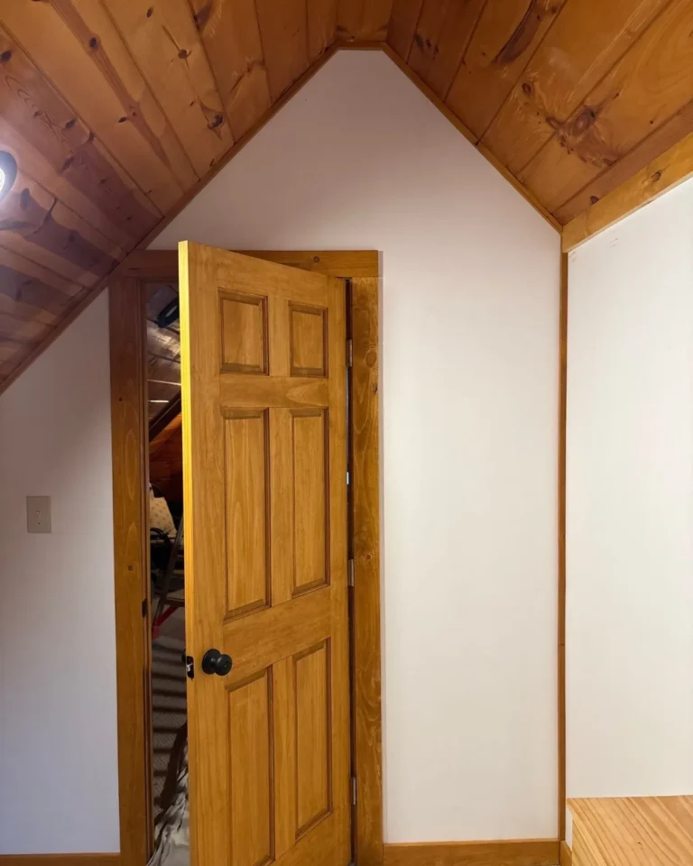 Finished wood door beneath a vaulted wood ceiling