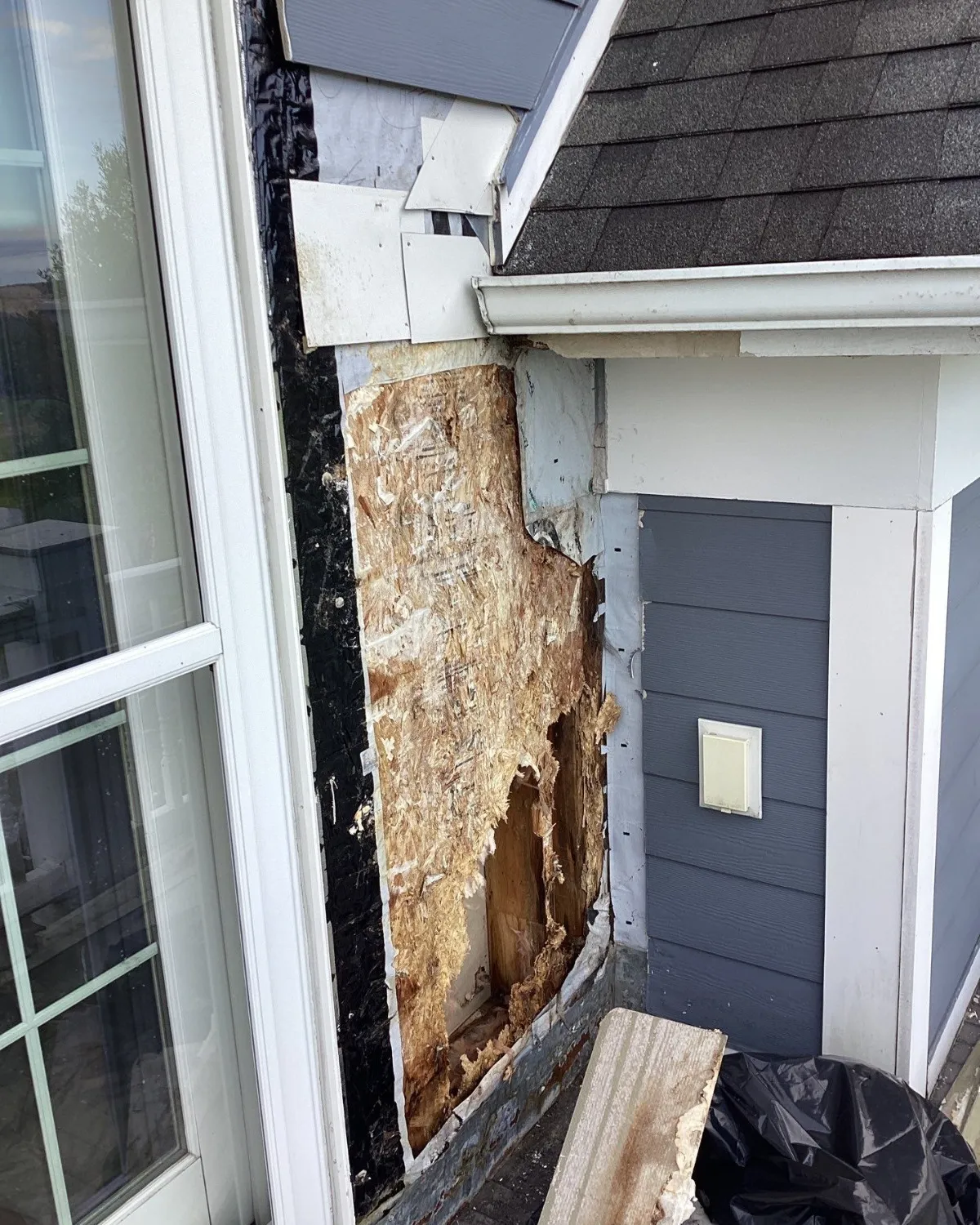 Damaged exterior wood exposed beside a doorway